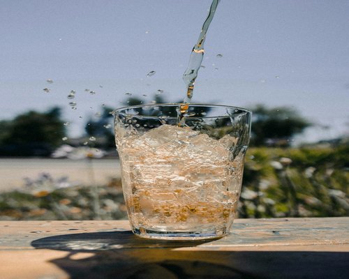 Fresh clear water pouring into a clean glass on a table with a natural background representing daily pure hydration habits